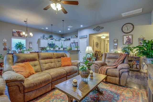 living room featuring ceiling fan with notable chandelier, light wood-type flooring, visible vents, and recessed lighting