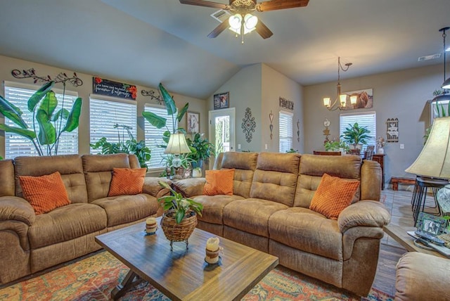 living room with vaulted ceiling, ceiling fan with notable chandelier, and visible vents