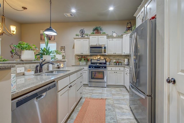 kitchen with stainless steel appliances, a sink, visible vents, white cabinets, and decorative backsplash