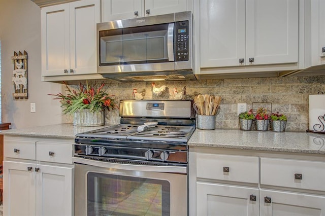 kitchen with light stone counters, appliances with stainless steel finishes, white cabinetry, and tasteful backsplash