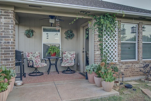 entrance to property featuring ceiling fan, visible vents, a shingled roof, and brick siding