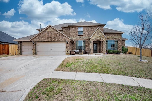 view of front of house featuring an attached garage, driveway, fence, and brick siding