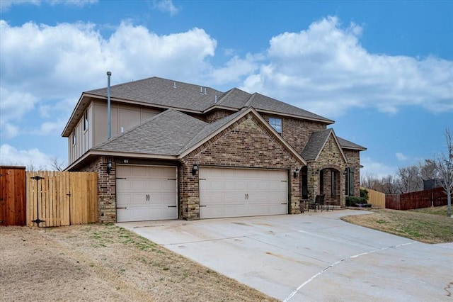 view of front of home featuring roof with shingles, brick siding, fence, a garage, and driveway