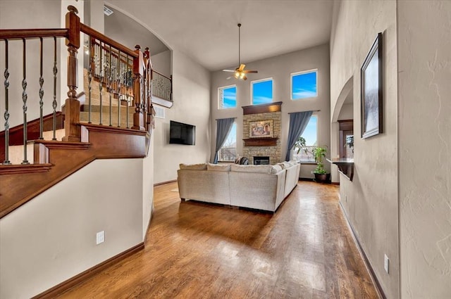 living area with baseboards, ceiling fan, wood finished floors, stairs, and a fireplace