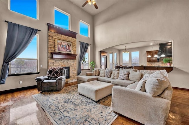 living area featuring plenty of natural light, arched walkways, wood finished floors, and a stone fireplace