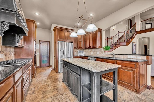 kitchen with a center island, stainless steel appliances, stone tile flooring, a sink, and a peninsula