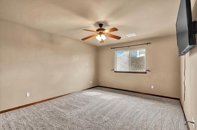 carpeted spare room featuring a ceiling fan, visible vents, and baseboards