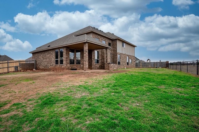 back of house featuring a yard, brick siding, a patio area, and a fenced backyard