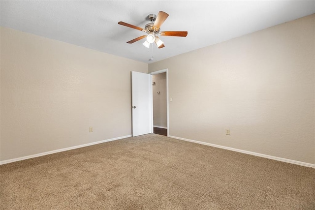 carpeted spare room with a ceiling fan and baseboards