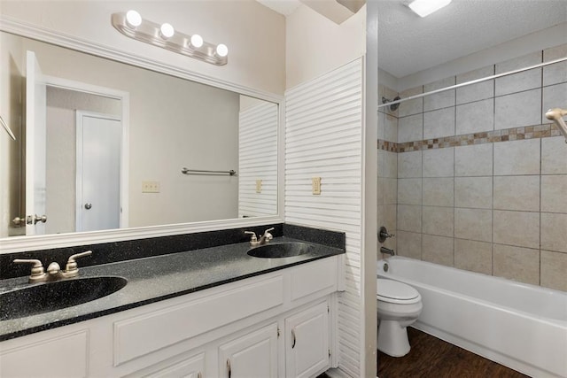 full bathroom featuring double vanity, toilet, wood finished floors, and a sink