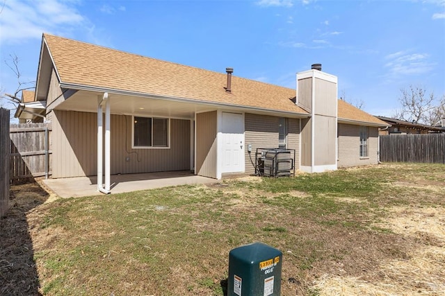 back of house featuring a patio area, a chimney, a shingled roof, and fence