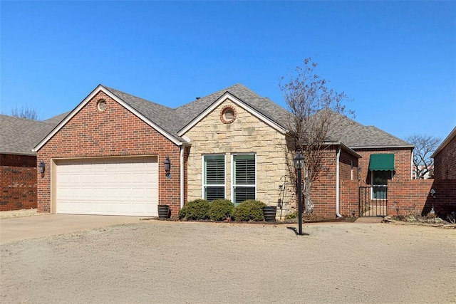 view of front of house featuring driveway, stone siding, roof with shingles, an attached garage, and brick siding