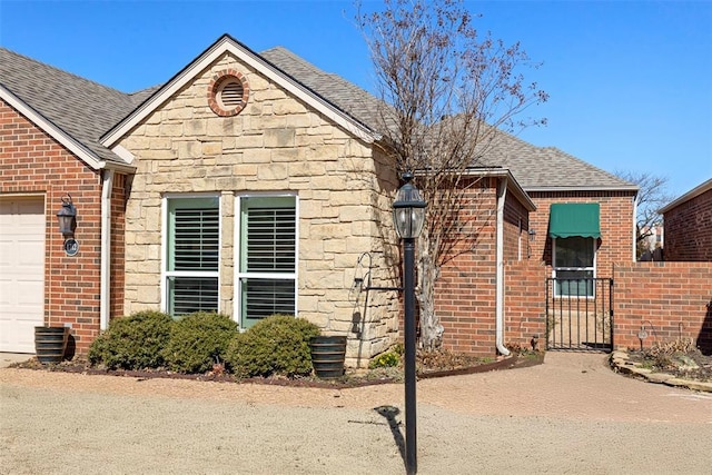 exterior space with stone siding, roof with shingles, and brick siding