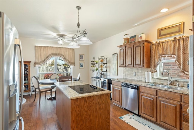 kitchen featuring tasteful backsplash, a kitchen island, appliances with stainless steel finishes, dark wood-style flooring, and a sink