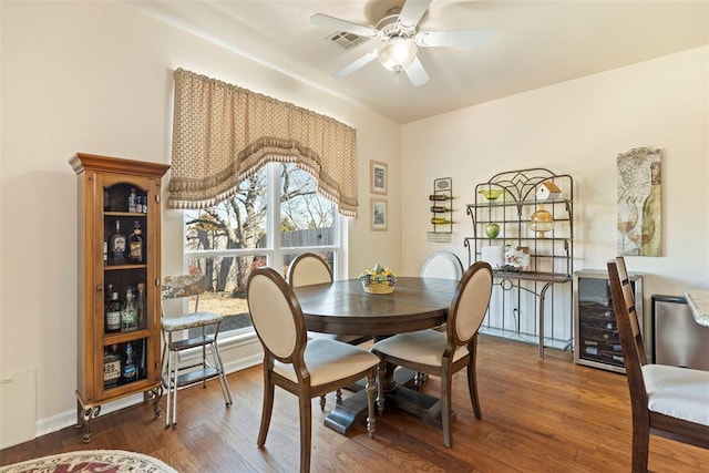 dining room featuring a ceiling fan, beverage cooler, visible vents, and wood finished floors