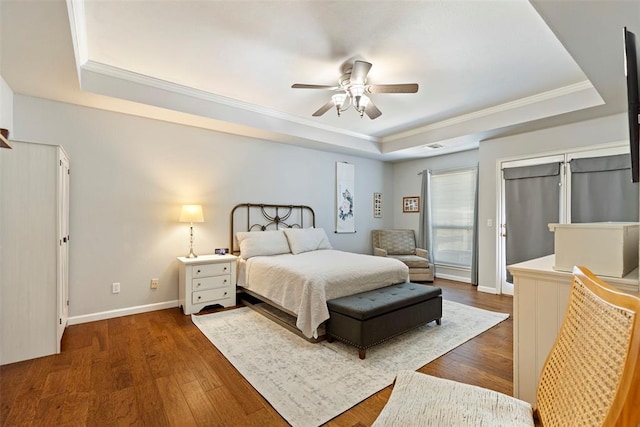 bedroom with ornamental molding, a tray ceiling, and wood finished floors