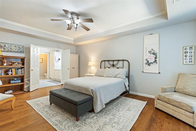 bedroom featuring ornamental molding, wood finished floors, a raised ceiling, and baseboards