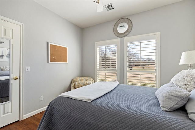 bedroom with wood finished floors, visible vents, and baseboards