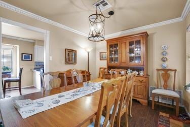 dining area featuring a chandelier, ornamental molding, dark wood finished floors, and baseboards