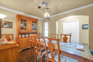 dining room featuring arched walkways, a chandelier, visible vents, dark wood-style floors, and crown molding