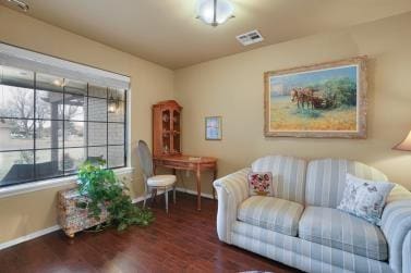 living area featuring visible vents, baseboards, and wood finished floors