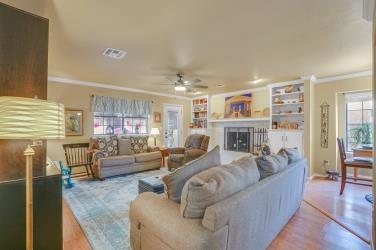 living area featuring visible vents, ceiling fan, ornamental molding, wood finished floors, and a fireplace