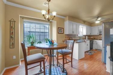 dining area featuring light wood finished floors, visible vents, ornamental molding, baseboards, and ceiling fan with notable chandelier