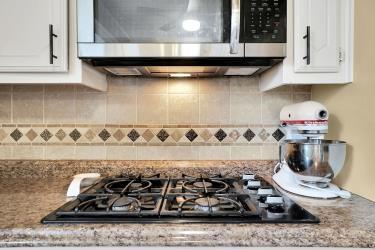 details featuring stainless steel appliances, light stone counters, white cabinetry, and decorative backsplash