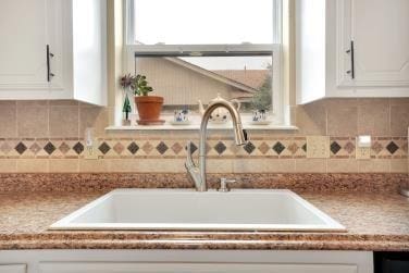 room details with white cabinetry, backsplash, and a sink