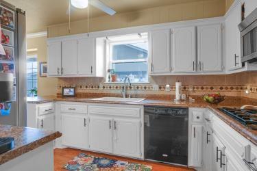 kitchen featuring black appliances, a sink, white cabinetry, and decorative backsplash