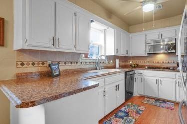 kitchen with tasteful backsplash, stainless steel microwave, white cabinetry, a sink, and dishwasher