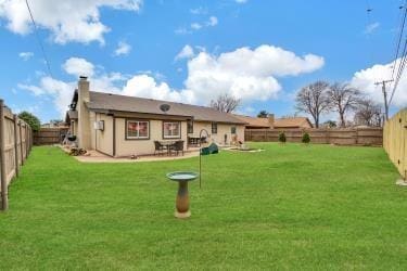 rear view of house with a fenced backyard, a lawn, and a patio