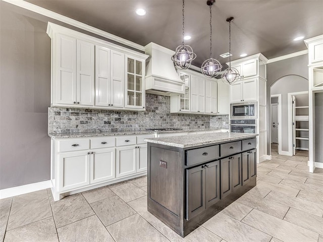 kitchen with tasteful backsplash, premium range hood, stainless steel appliances, arched walkways, and white cabinetry