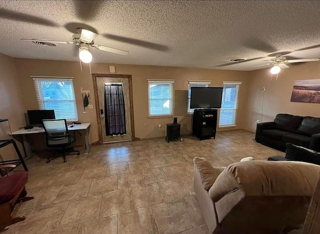 living area with a ceiling fan, visible vents, and a textured ceiling