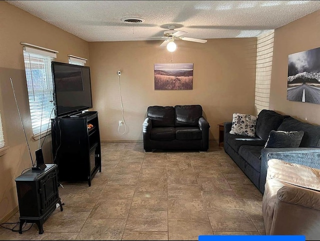 living area featuring visible vents, a textured ceiling, and ceiling fan