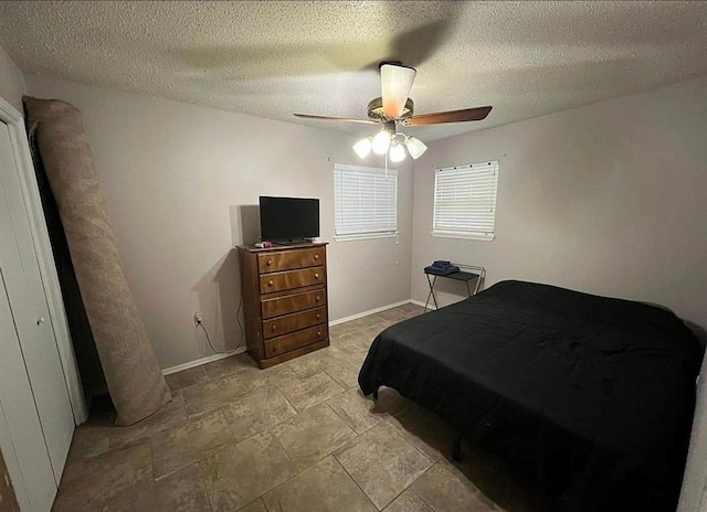 bedroom featuring a ceiling fan, baseboards, and a textured ceiling