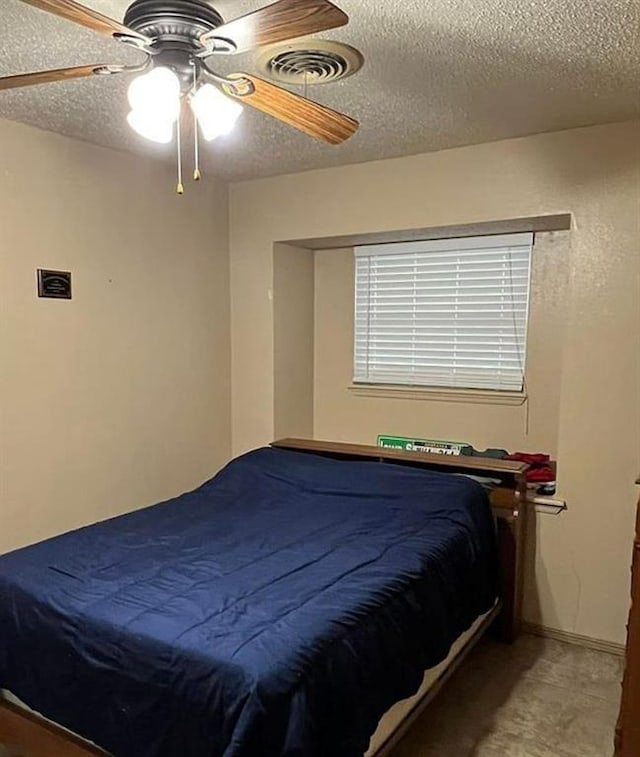 bedroom featuring ceiling fan, visible vents, and a textured ceiling