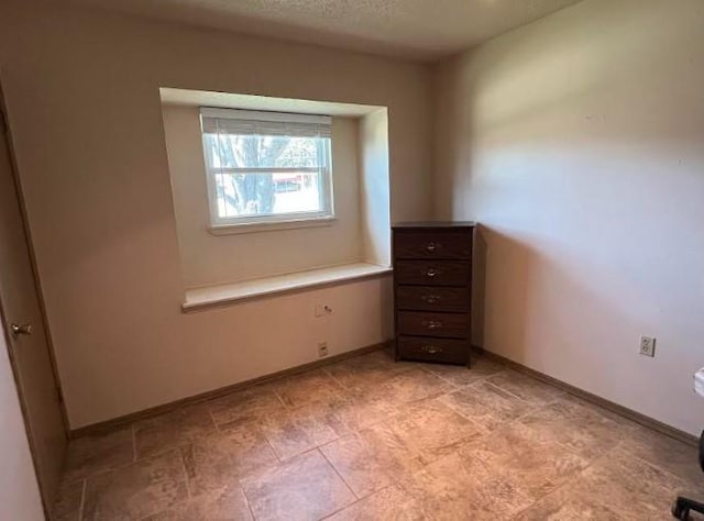 spare room featuring baseboards and a textured ceiling