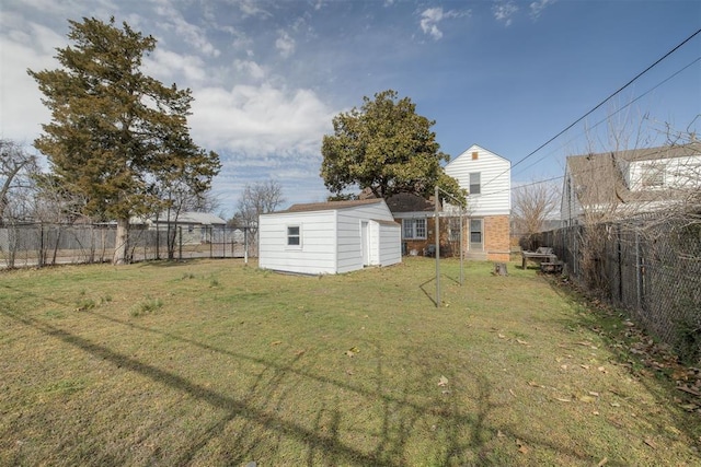 view of yard with a storage shed, a fenced backyard, and an outbuilding