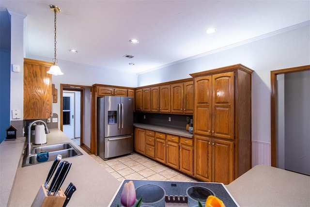 kitchen with stainless steel fridge, visible vents, brown cabinetry, hanging light fixtures, and a sink