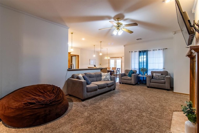 carpeted living room featuring a ceiling fan, a fireplace, visible vents, and crown molding