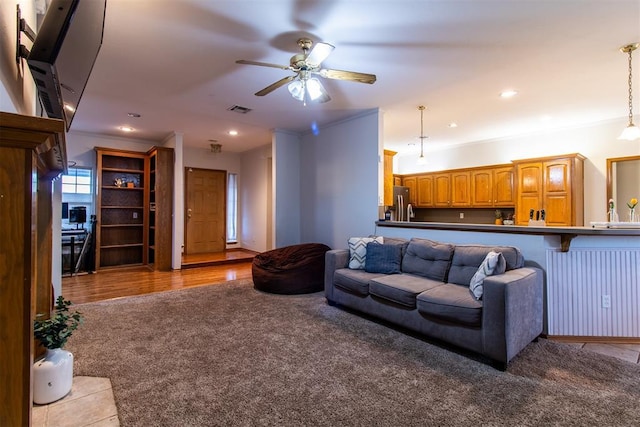 living area featuring ceiling fan, recessed lighting, carpet flooring, visible vents, and crown molding