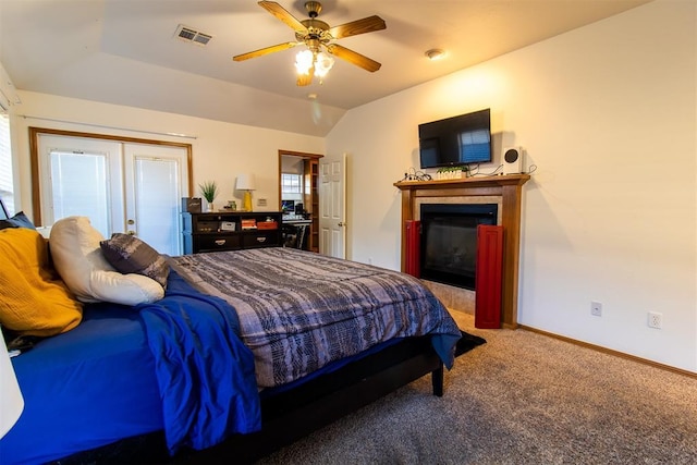 carpeted bedroom featuring baseboards, visible vents, a glass covered fireplace, ceiling fan, and vaulted ceiling