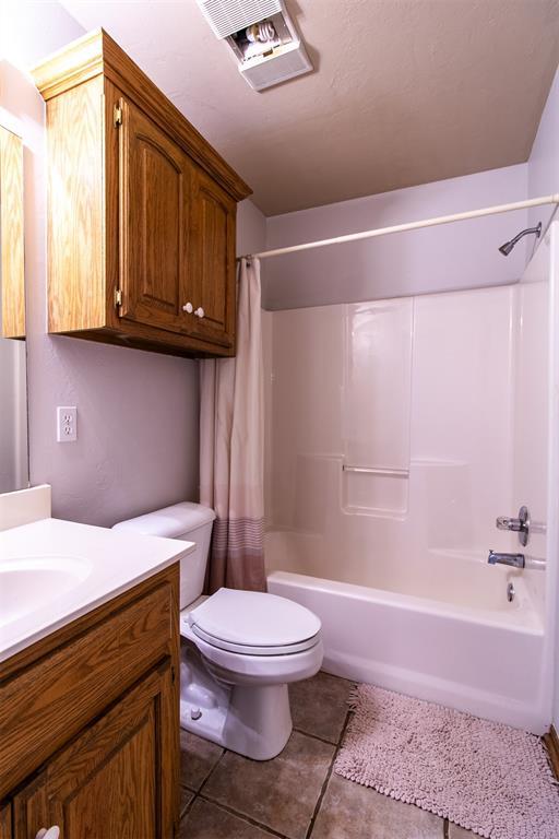 full bath with shower / tub combo, visible vents, toilet, tile patterned floors, and vanity