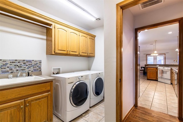 laundry room featuring cabinet space, visible vents, light tile patterned flooring, a sink, and independent washer and dryer