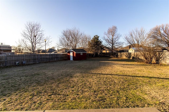 view of yard with a shed, a fenced backyard, and an outbuilding