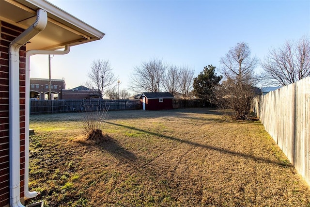 view of yard with an outbuilding, a storage unit, and a fenced backyard