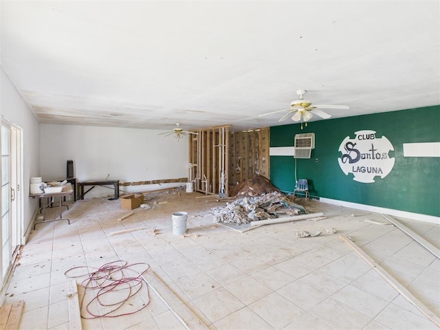 interior space featuring baseboards, an AC wall unit, and ceiling fan