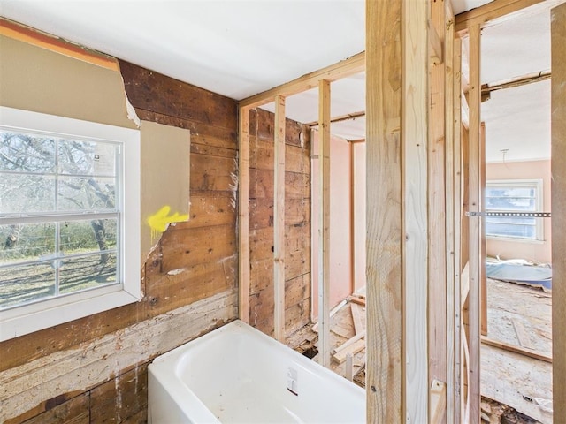 full bathroom with wooden walls and a tub to relax in