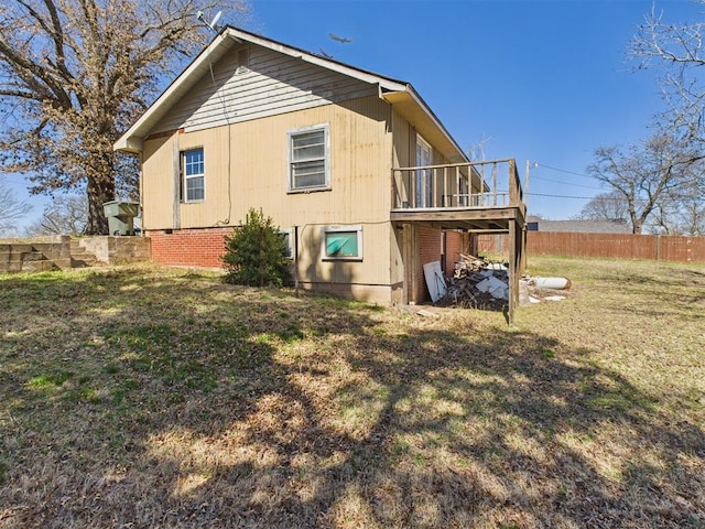 back of property with brick siding, a wooden deck, a yard, and fence